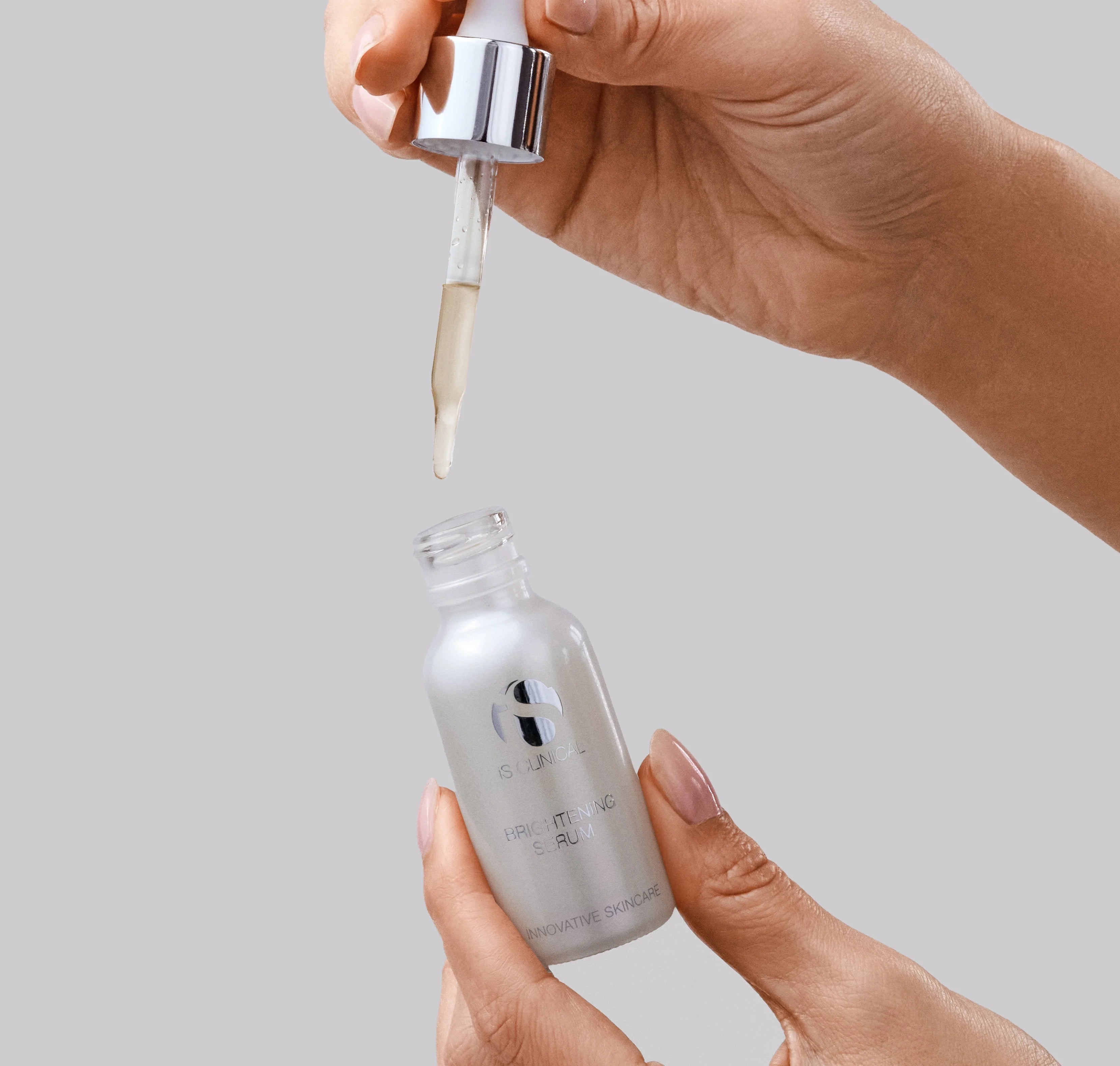 iS Clinical Brightening Serum, hand holding the dropper