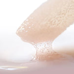 Close-up of a lip conditioner applicator with a drop of lip conditioner on a white background