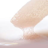 Close-up of a lip conditioner applicator with a drop of lip conditioner on a white background