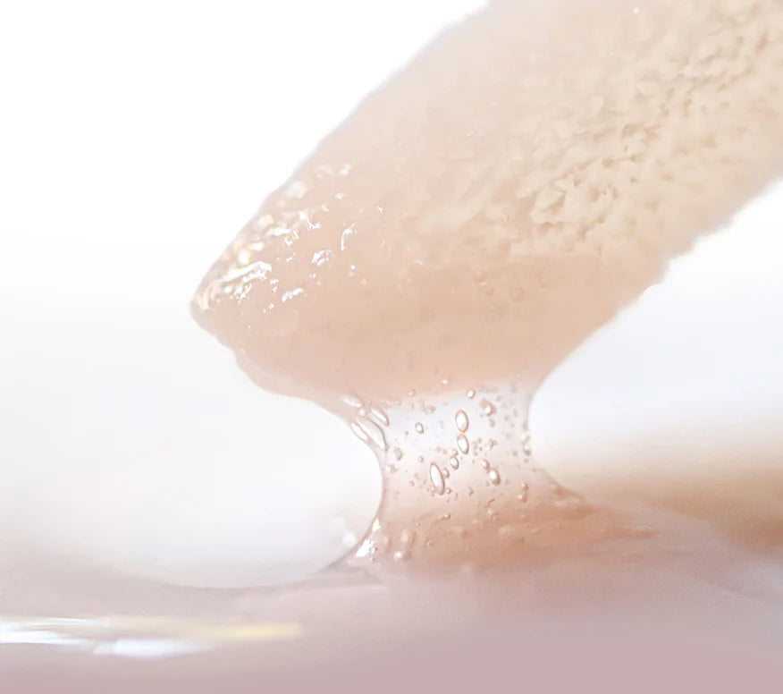 Close-up of a lip conditioner applicator with a drop of lip conditioner on a white background